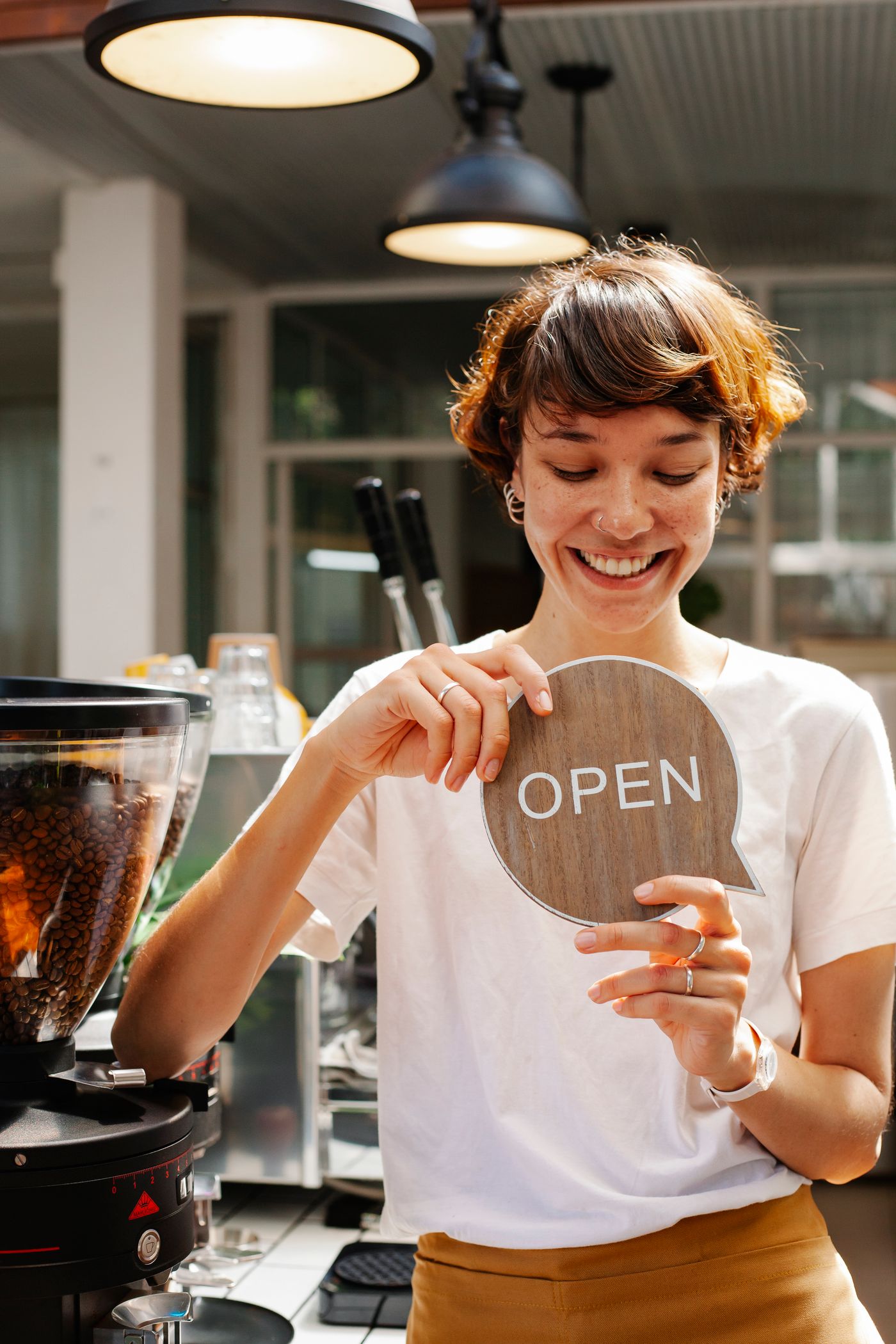 Cafe owner smiling and holding an open sign